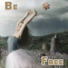 A person in a dark top and light pants reaches upward toward a small orange object against a cloudy sky background with text reading 'Be' and 'Free' in brown letters.