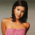 Pixelated image of a person with long dark hair wearing a pink strapless top against a muted gray background.