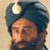 Static pixelated image of a person wearing a dark blue turban with a white circular emblem on the front, set against a light beige background.