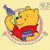 Yellow bear in red shirt holding green balloon with blue tip, set against light yellow background.