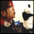 Pixelated static image of a person with red hair and dark clothing holding a blue object, next to a black-and-white figure in motion against a light background.