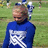 A pixelated image shows a person in a blue long-sleeve shirt with a white pattern standing outdoors on grass, next to a blue with pixelated text