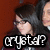 Pixelated image of a person with dark hair and glasses, wearing a dark jacket over light clothing against a brown background, with text overlay reading 'Crystal?' in blocky white letters.