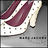 A pair of white high-heeled shoes with black polka dots and maroon insoles, positioned on a gray background with 'MARC JACOBS' text below.