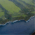 Pixelated landscape with green terrain, blue water, and white wave-like patterns along the shoreline.