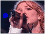 A woman with curly red hair sings into a microphone in three showing different poses and expressions