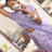 Pixelated image of a person lying on their back with arms behind head, wearing purple pants and light-colored top against blurred background.