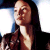 A pixelated close-up of a person with long dark hair, wearing a dark top, against a bright background with blue and white tones.