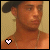 A 50x50 pixel animated buddy icon showing a person with dark hair and a black cap, featuring two frames where the lower-left heart symbol changes from white to black.