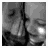 Black-and-white pixelated image of two figures standing side-by-side with a vertical pole between them, one figure holding an object near the pole.