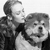 Black-and-white pixelated image of a person in dark clothing holding a large dog with light fur against a plain background.