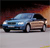 A blue sedan with a black roof is positioned on a light gray surface against a gradient background transitioning from dark red to orange.