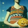 A person in a patterned sweater holds a carved pumpkin under a blue sky with scattered white dots.