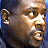Pixelated close-up of a person's face with light brown skin tone, visible ear, and dark hair against a blue background.