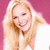 A static image of a person with long blonde hair wearing a white top against a solid pink background.