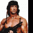 Pixelated image of a shirtless muscular person with long dark hair wearing black straps over shoulders against white background.