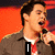 A person holding a microphone against an orange background with text overlays changing across frames.