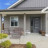 Pixelated image of a single-story house with gray siding, dark door, and window under blue sky.