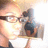 Pixelated image of a person with light skin wearing dark glasses and holding a small animal near their face against a bright background.