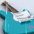 Pixelated turquoise electric guitar with brown neck and white pickguard, featuring a heart symbol that alternates between pink outline and black fill.