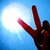 Pixelated image of a red hand making a peace sign against a blue gradient background with a bright white circular light effect on the left.