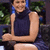 Pixelated image of a person with light skin wearing dark blue sleeveless top and white shorts, arms crossed in front of torso against blurred green background.