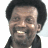 A pixelated image of a smiling person with short dark hair wearing a dark jacket over a light shirt, alongside blue text reading "Good Times" and "OriginalIcons.com" on black backgrounds.