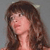 Static pixelated image of a person with long brown hair against a gray background, rendered in low resolution with visible dithering and color blending.