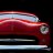 A static pixelated image of a red vehicle with horizontal light streaks and dark background, appearing as motion blur.