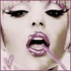 Close-up of a person's face with exaggerated makeup, holding a pink straw in their mouth, and a small heart symbol on the left side.
