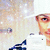 A pixelated image of a person wearing a white cap and dark clothing, holding a white object with visible text.