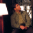 Static 48x48 pixel icon showing a person in brown clothing with orange hands and head, next to a white lamp on dark background.