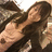 Pixelated image of a person with long dark hair wearing a dark sleeveless top, lying down with arms crossed over chest.