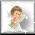 Pixelated angel figure with brown hair holds pink flower, green dress, gray wings against white background; animation shows subtle movement of the head and hand.