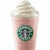 A pink beverage in a cup with whipped cream topping and a green circular logo on the side.