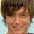 Pixelated close-up of a person with brown hair and light skin, wearing an earring, against a blurred background with the word UGLY overlaid in black text.
