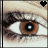 Brown eye with black pupil and white reflection, eyelashes visible, light skin tone, heart symbol in top-right corner.