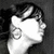 Black-and-white profile of a person with short dark hair and large hoop earrings, showing three sequential head positions against a solid background.