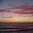 Pixelated sunset over water with gradient sky transitioning from deep blue to orange and yellow near the horizon.