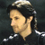 Pixelated image of a person with dark hair and light skin, wearing a black shirt with white stripes on the collar, next to text reading "Sir Guy of Gisborne" in stylized font.