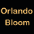 Pixelated image with text 'Orlando Bloom' in yellow block letters on black background, right side shows partial face of a person.