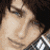 Two men with dark hair appear side-by-side in a pixelated image; one wears a checkered shirt, the other a white top.
