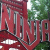 Pixelated red and green image with abstract shapes and partial text elements, showing a building-like structure with vertical lines and a green background.