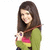 A woman with long brown hair wears a green cardigan over a pink and yellow striped shirt, holding a purple object near her chest.