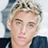 Pixelated image of a person with light hair and blue eyes on a dark blue background with pink text elements.