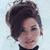Static 50x50 pixel icon showing a close-up of a person's face with dark hair styled upward, wearing a black top against a light blue background.