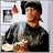 A person in a black cap and dark sweater holds food while standing near framed pictures, with text appearing on the right side of the image.