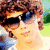 Pixelated image of a person with brown curly hair and sunglasses, showing four variations including text overlays and symbols.