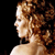 Pixelated profile view of a person with curly brown hair against a black background, showing shoulder and neck area.