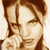 Pixelated static image of a person's face with brown hair and light skin tones, rendered in sepia-toned colors on a white background.